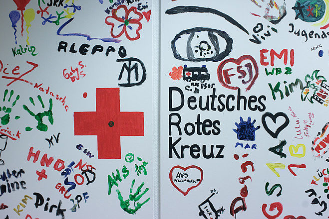 Buntes Wandbild aus Fingerfarben mit dem Logo des Deutschen Roten Kreuzes.