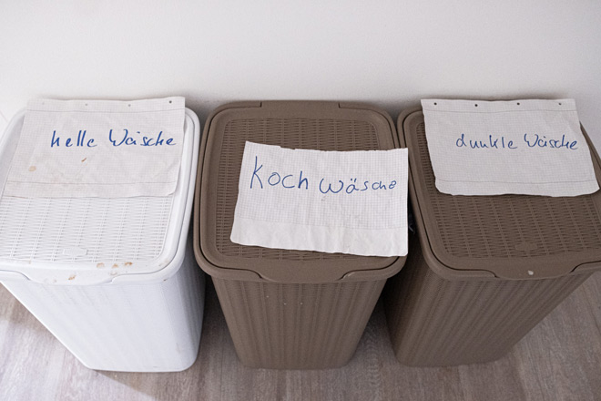 Drei Wäschekörbe, beschriftet mit "helle Wäsche", "Kochwäsche" und "dunkle Wäsche".