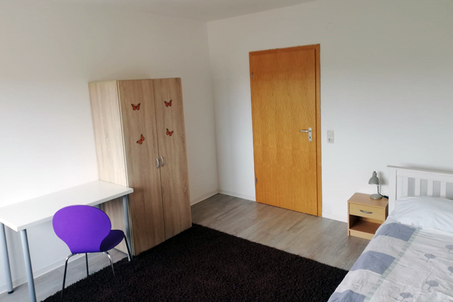 Ein Zimmer mit Bett, Schrank und Tisch in Grefrath.