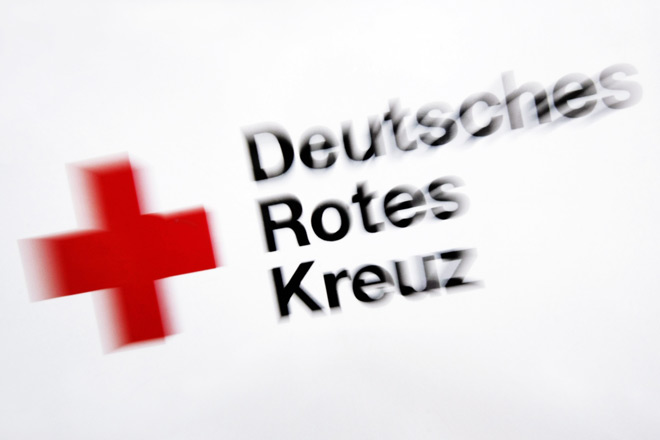 Leitlinien DRK-Logo auf weißem Grund, fotografisch leicht unscharf inszeniert.