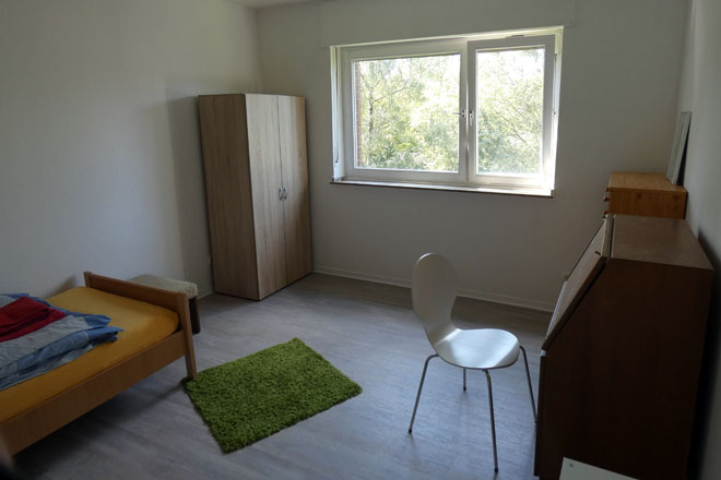 Ein Zimmer mit Bett, Schrank und Tisch in Krefeld.
