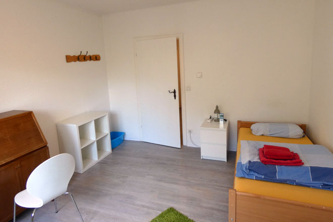 Ein Zimmer mit Bett, Regal und Tisch in Krefeld.