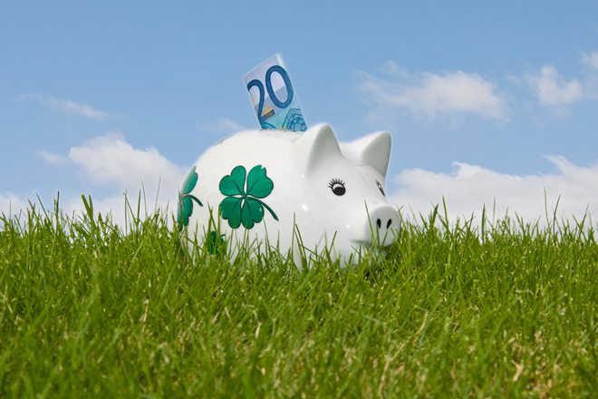 Geldspenden Weißes Sparschwein auf der grünen Wiese vor blauem Himmel.