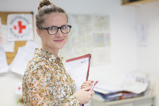 Blonde Frau mit Brille und geblümter Bluse.