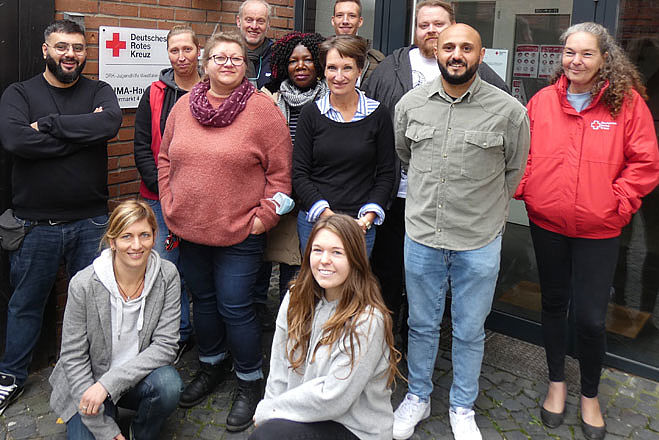 Das Team der DRK Jugendhilfe Westfalen-Lippe steht vor dem Eingang zum Gruppenbild zusammen.