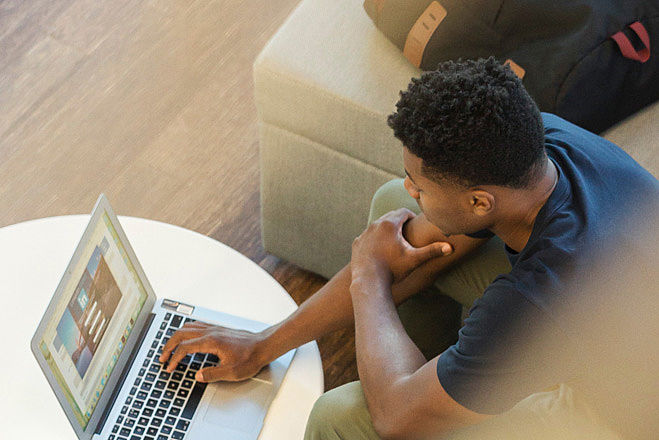 Ein männlicher Teenager mit Migrationshintergrund arbeitet an einem Laptop.