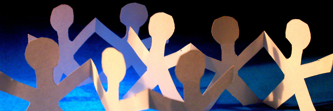 Eine Gruppe von Scherenschnitt-Papiermännchen vor blauem Hintergrund.