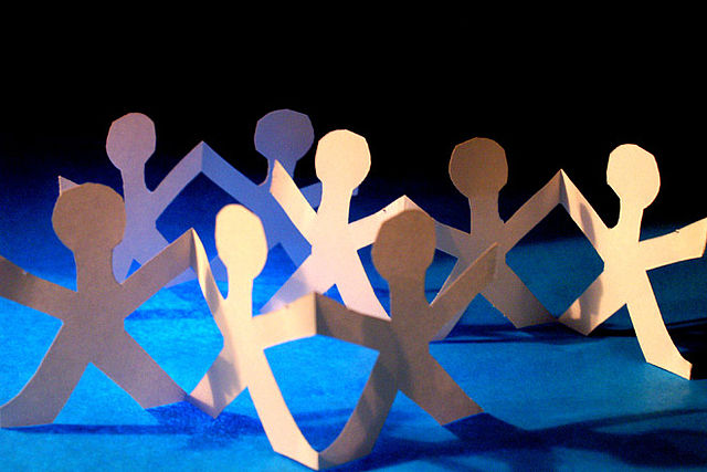 Eine Gruppe von Scherenschnitt-Papiermännchen vor blauem Hintergrund.