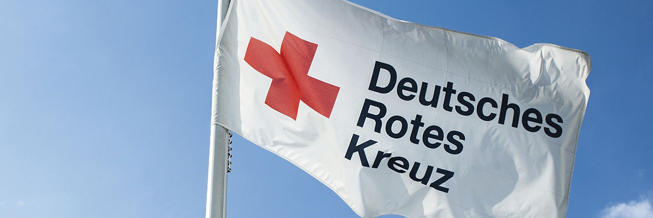 Weiße DRK-Fahne vor blauem Himmel