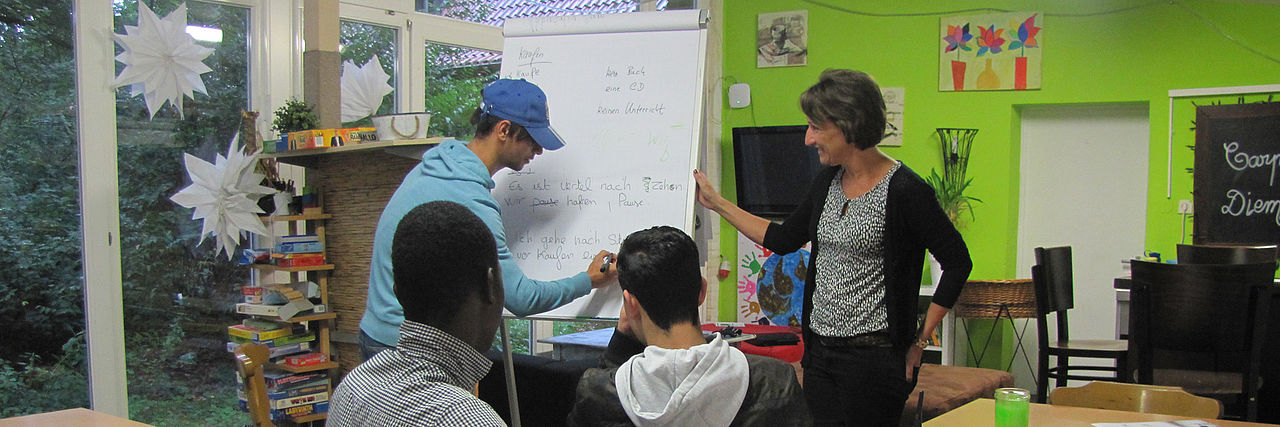 Eine Frau unterrichtet drei Jugendliche und erklärt etwas an der Flipchart.