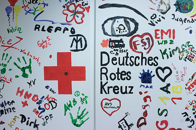 Buntes Wandbild aus Fingerfarben mit dem Logo des Deutschen Roten Kreuzes.